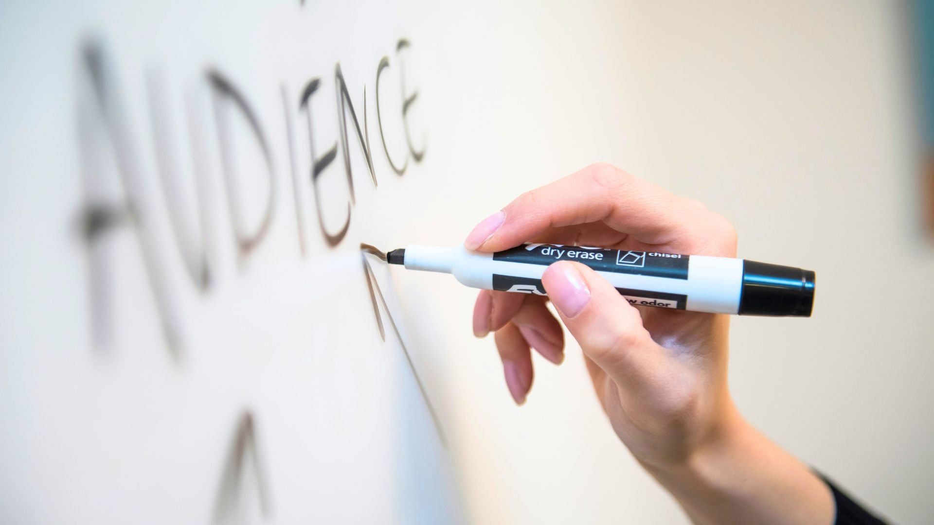 Horizontales Bild einer Hand mit Stift, welche auf ein Whiteboard schreibt